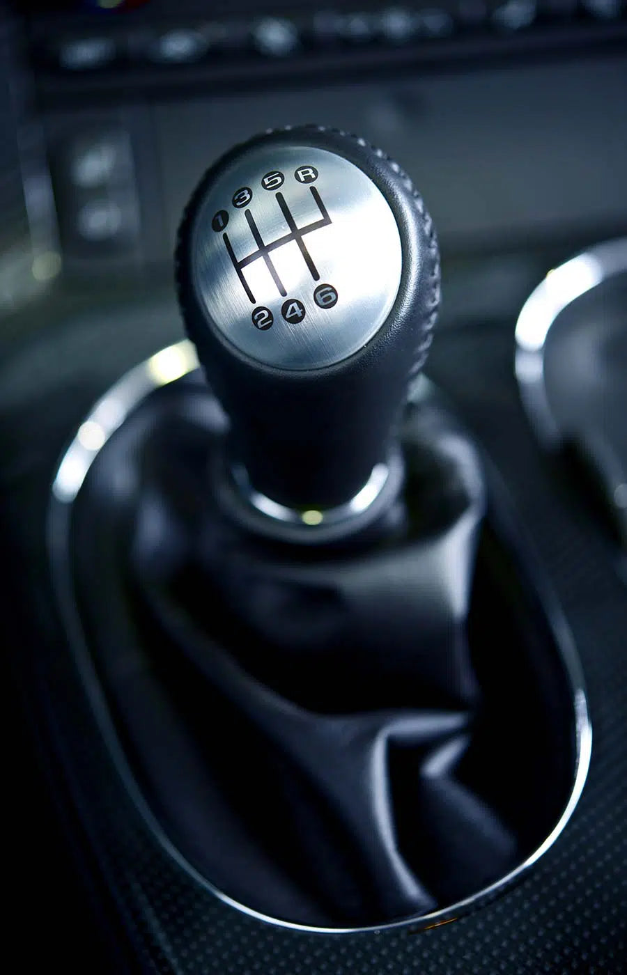 Nahaufnahme des Schalthebels eines Autos, auf dem die Zahlen 1 bis 6 und R für die verschiedenen Gänge zu sehen sind, wobei der Hintergrund leicht verschwommen ist.